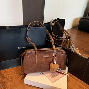 Brown suede minimalist tote bag with bear charm and metallic brand plaque detail