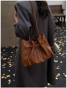 Close-up of brown tote bag featuring drawstring knots and pleated detail for autumn