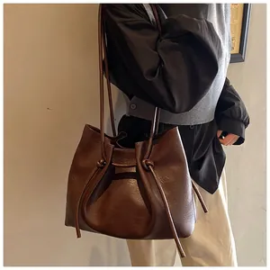 Detail of the minimalist dark brown leather tote bag with knotted shoulder strap design
