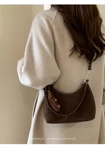 Detail of minimalist dark brown suede crescent bag featuring side tassels and beaded decor