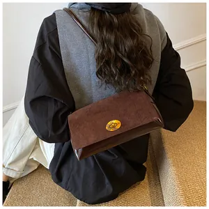 Détail du sac à bandoulière marron avec boucle en métal doré vintage porté par un modèle