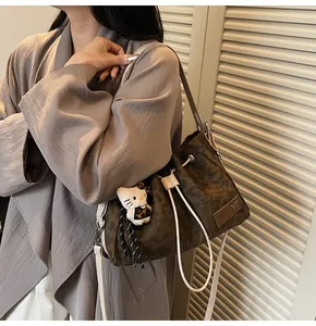 Detail of leopard print canvas bucket bag with plush charm and drawstring closure