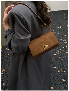 Détail du sac à bandoulière en daim marron avec fermoir rotatif doré et texturé