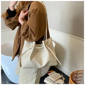 Detail of cream tote bag with stylish pleated knot handle and smooth leather texture