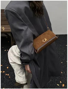 Détail macro du sac à bandoulière vintage en cuir marron avec fermoir rotatif doré élégant