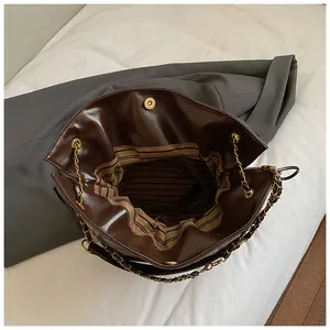 Detail view of the deep brown tote bag interior with striped lining and gold magnetic closure