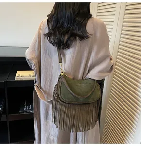 Detail view of dark green suede shoulder bag with long fringes and gold hardware