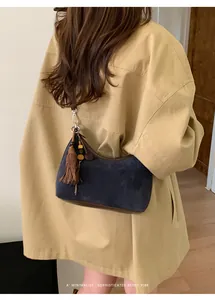 Detail showing navy suede hobo bag texture with tassel beads and brown leather trim