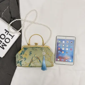 Detailed size comparison of green floral brocade qipao bag with pearls and tassel