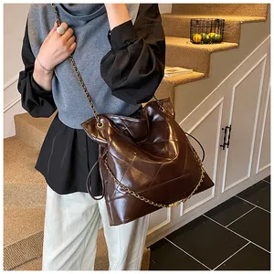Detailed view of dark brown quilted leather tote with gold chain strap on model