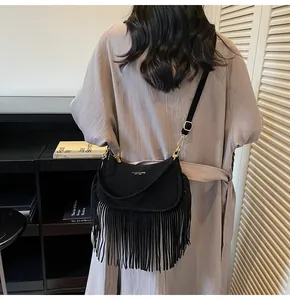Rear view of model wearing a vintage black fringed crossbody bag with gold hardware