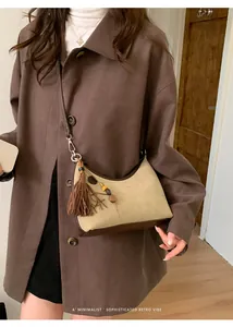 Detail of minimalist retro hobo bag with brown tassels and wooden bead pendant on model