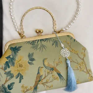 Detailed view of pale green satin evening bag with floral embroidery and detachable charm