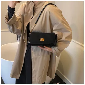 Détail d'un sac à bandoulière vintage en cuir verni noir avec fermoir doré ovale