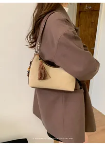 Suede baguette shoulder bag with leather trim and tassel detail shown on model