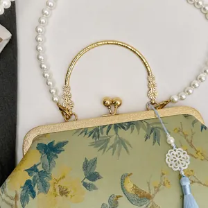 Detail of bird and floral embroidery on green fabric with a pearl strap and gold handle