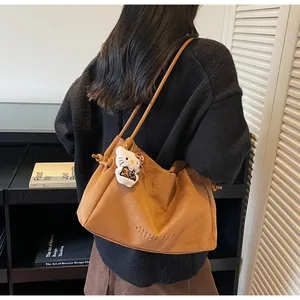 Détail du sac cabas en daim marron avec nœud latéral et accessoire en peluche doux