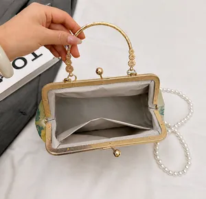 Detail view of vintage floral evening bag with golden metal handle and pearl strap