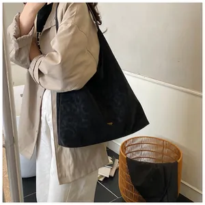 Détail du cabas noir en daim à motif léopard avec logo doré sur trench-coat