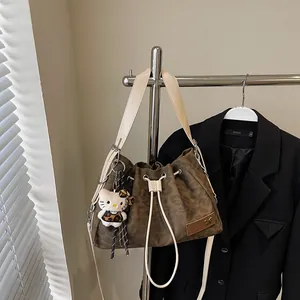 Leopard print bucket bag with drawstring closure and plush pendant on a hanger