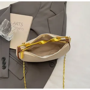 Detail view of beige textured bag with gold twisted handle and interior metal chain strap