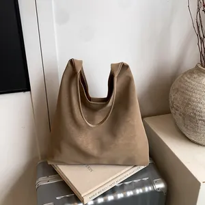 Grand sac cabas minimaliste kaki clair en cuir mat sur une valise argentée pour le bureau