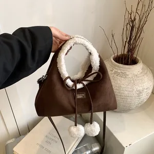 Brown suede bucket bag with white faux fur trim and plush pom-poms for winter