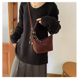 Detail of vintage brown suede crossbody bag with woven handle and colorful beaded tassels