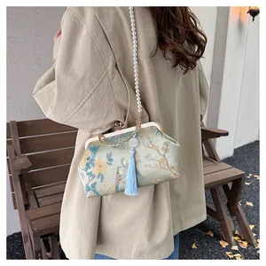 Detail of silk qipao bag with floral embroidery, pearl strap, and blue silk tassel