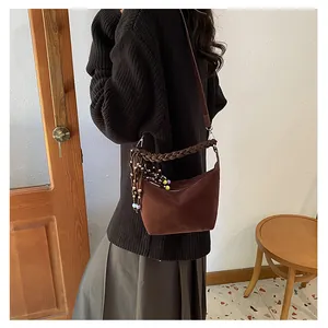 Detail of vintage matte dark brown crossbody bag with braided handle and beaded tassel charm