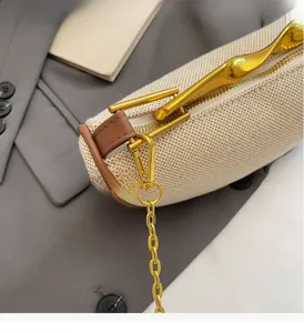 Detail of durable gold hook and zipper head on cream woven crossbody bag with chain