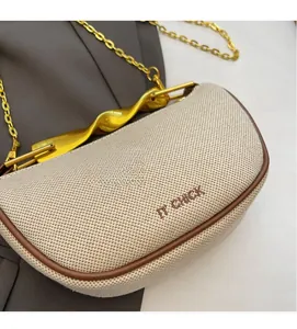 Detail of woven dumpling bag with gold wavy handle and IT CHICK embroidery