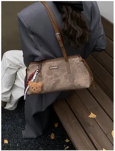 Detailed view of brown retro shoulder bag with fashion bags metal logo and bear charm