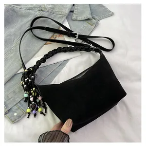 Detail of black suede bag with woven handle and colorful beaded tassel pendant