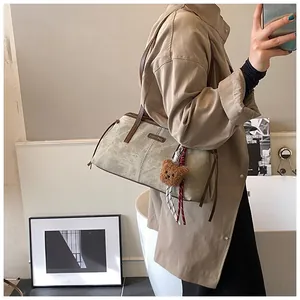 Detailed view of grey-green canvas tote bag with brown leather handles and a cute bear charm
