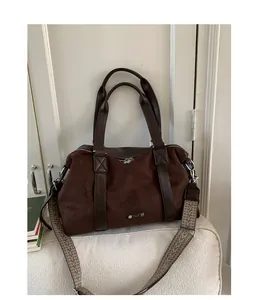 Detail of a large brown suede tote bag with ethnic style woven strap and metal logo plate