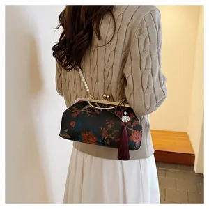 Detail of vintage floral frame bag with pearl strap and deep red tassel charm accessory