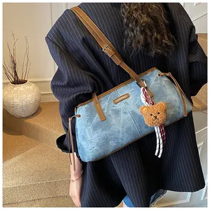 Detail of blue denim shoulder bag with brown leather trim and cute bear charm