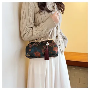 Detail of vintage floral fabric handbag with golden metal clasp and pearl strap