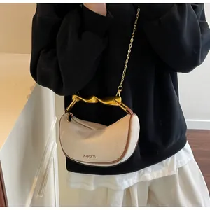 Detail of cream dumpling bag with twisted gold handle and woven fabric texture