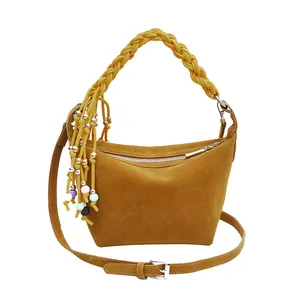Chic mustard yellow frosted leather handbag with woven handle and colorful tassel charm