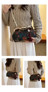 Detail of vintage floral embroidery fabric bag with golden metal clasp and pearl strap