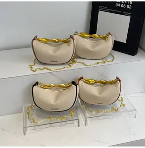 Detail of canvas crescent bag featuring gold metal handle and chain strap with logo