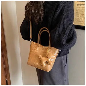 Detail of woven faux leather mini tote in caramel brown with matching dog charm accessory