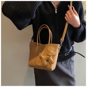 Detail of a brown woven crossbody bag with a cute dog pendant and detachable strap