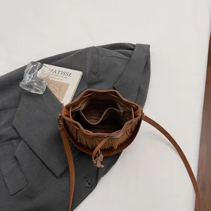 Brown suede bucket bag with stylish tassels and adjustable strap shown from a top view