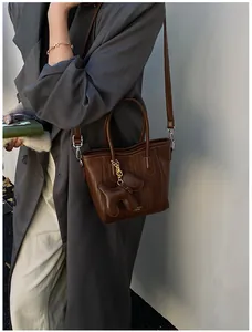 Detail view of deep brown leather tote bag with a small dog charm and fine metal hardware