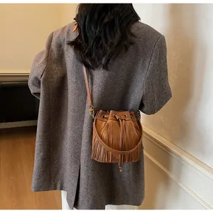 Detailed shot of a brown fringe bucket bag with drawstring closure and slim shoulder strap