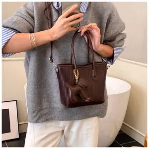 Detail of dark brown woven tote bag featuring a cute puppy charm and adjustable strap