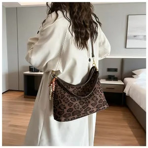 Detailed view of leopard print hobo bag with leather trim and tassel on beige trench coat